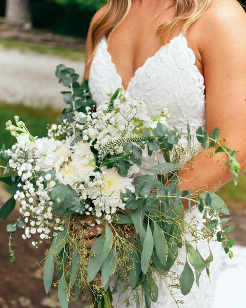 Una novia sostiene su ramo de flores blancas y eucalipto